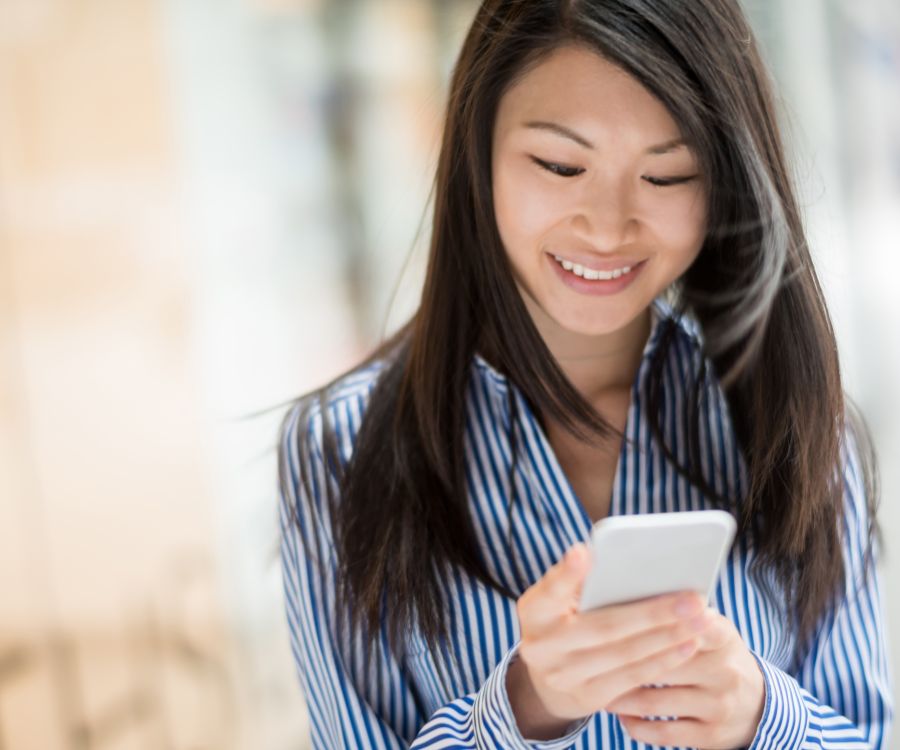 Image depicting a smiling young woman engaging the Expense Claims module from Frontier Software on her mobile phone.