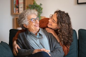 Older woman and younger woman hugging and looking at one another