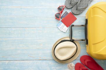 Holiday suitcase, flipflops, sunglasses, sunhat, passport and boarding passes.