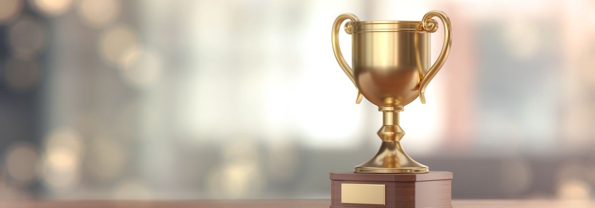 Golden trophy cup with walnut wooden base sitting on a desk